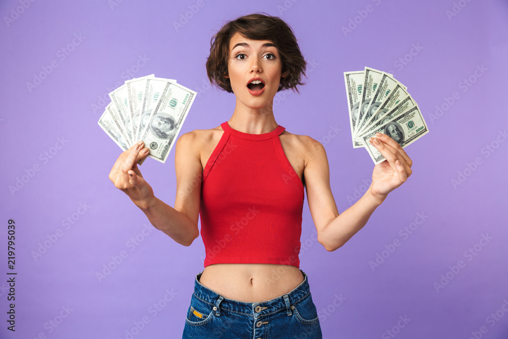 Wall mural surprised pretty brunette woman posing with money