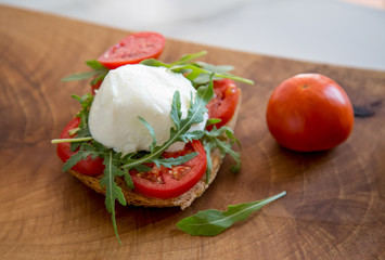 Italian style toast with light bread, arugula, tomato and mozzarella cheese 