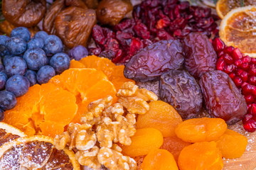 Platter of Festive Christmas Fruits.  Wooden Platter loaded with a selection of fresh and dried Christmas Fruits.  Decorated with Holly, Cinnamon and Christmas parcels.