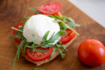 Italian style toast with light bread, arugula, tomato and mozzarella cheese 