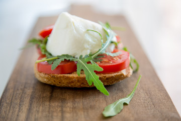Italian style toast with light bread, arugula, tomato and mozzarella cheese 