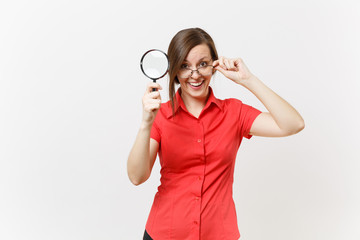 Portrait of fun pretty young business teacher woman in red shirt glasses holding, looking through magnifying glass isolated on white background. Education or teaching in high school university concept