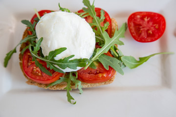 Italian style toast with light bread, arugula, tomato and mozzarella cheese 