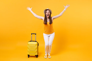 Traveler tourist woman in summer casual clothes, hat with suitcase isolated on yellow orange background. Female passenger traveling abroad to travel on weekends getaway. Air flight journey concept.