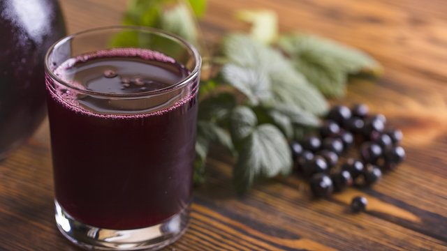 Fresh blackcurrant juice with some fruits on wooden background