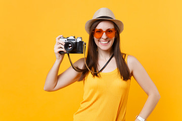 Tourist woman in summer casual clothes, hat take picture on retro vintage photo camera isolated on yellow background. Girl traveling abroad to travel on weekends getaway. Air flight journey concept.