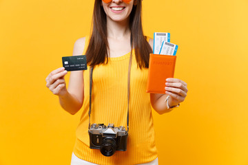 Cropped tourist woman in summer casual clothes holding credit card, passport tickets isolated on yellow orange background. Female traveling abroad to travel on weekends getaway. Air flight concept.