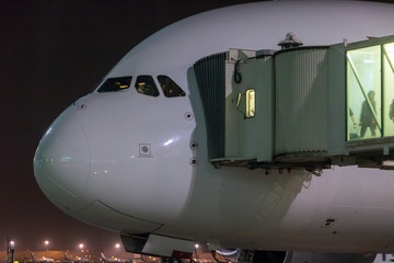 Passengers depart from the aircraft. The plane is standing by the tunnel at the night airport.
