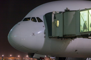Passengers depart from the aircraft. The plane is standing by the tunnel at the night airport.