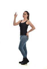  full length portrait of brunette girl wearing black single and jeans. standing pose in side profile. isolated on white studio background.