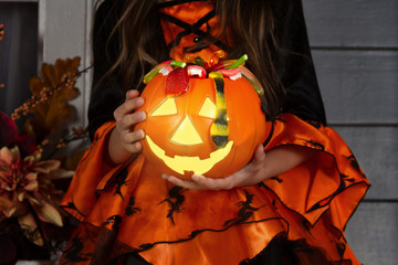 Close up of lantern jack halloween pumpkin basket for candies and sweets holded by young girl child...