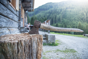 Axt in Holzblock vor Almhütte, Selbstversorgung