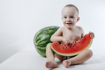 baby cheerful and funny with a piece of ripe juicy watermelon