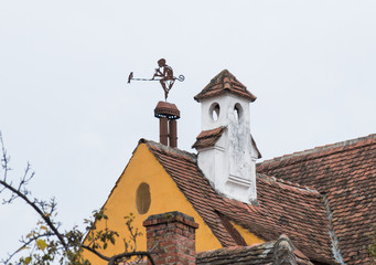 Weathervane in the form of a boy with a pipe and a bird on the roof of a dwelling house in the old...