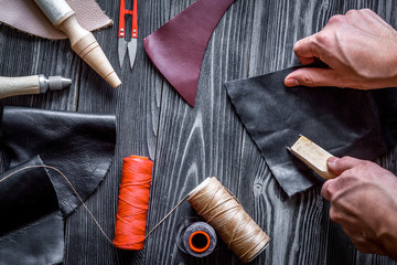 work in leather shop on dark wooden background top view