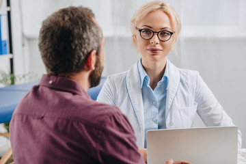 patient having appointment with physiotherapist in eyeglasses in hospital