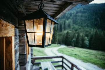 Laterne hängt auf Veranda vor einer Alm, Abend