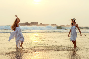 two sisters having fun at the sea at the sunset