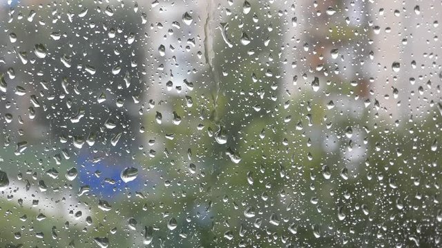 Lot of water drops on window. Rainy day, wet glass. Blurred city behind.
