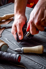 work in leather shop on dark wooden background close up