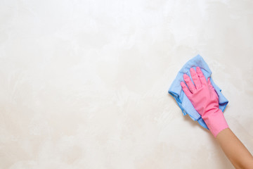 Employee hand in rubber protective glove with rag wiping vintage wall from dust. General or regular cleanup. Commercial cleaning company. Service concept. Copy space. Empty place for text or logo.