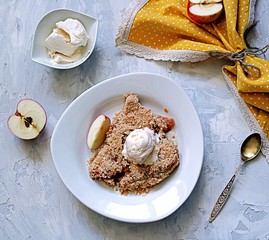 Apple crumble pie with whole-grain flour, oat flakes and cinnamon. Served warm with a vanilla ice cream ball.