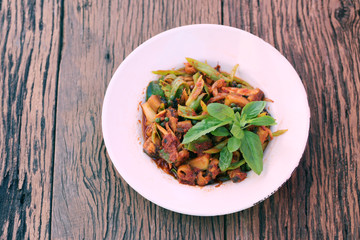 Stir spices with tropics eel in white dish on wooden floor.