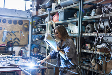 young woman welding in workshop