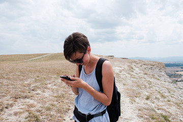 young woman hiker using mobile phone outdoor. Travel, vacation, trekking, hiking, connection, technology concept