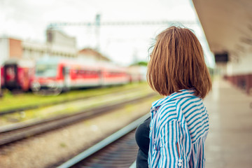 Fototapeta na wymiar Back view of a girl looking in the distance in a train station during the day