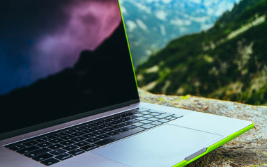 Laptop computer at the natural mountain background. Photo depicts notebook computer in the alpine heights. Freelance concept.