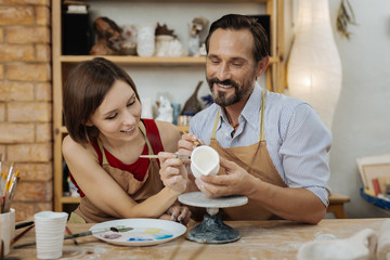 Work with wife. Dark-haired beaming potter feeling extremely happy while enjoying work with wife