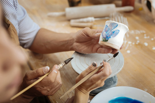 Two ceramists. Two creative inspired ceramists holding painting brushes while decorating handiwork