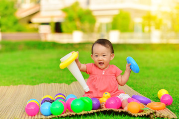 Cute Asian baby playing with toys in playground
