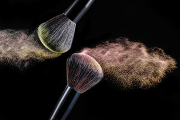 Make up brush with powder splashes on black background