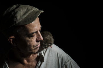 Fototapeta na wymiar Man with a rat on his shoulder in a dark.