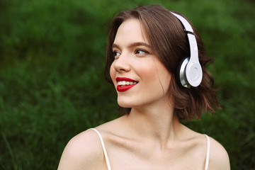 Smiling woman in dress and headphones listening music