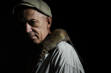 Man with a rat on his shoulder in a dark.