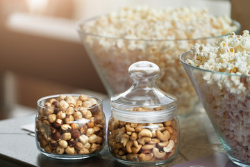 Glass bowls with popcorn and jars with nuts
