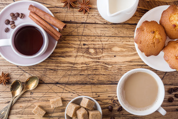 Breakfast and coffee for two persons, pastries, brown sugar and cinnamon with anise on a wooden background.