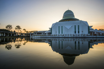 Obraz premium sunrise scenery at Seri Iskandar Public Mosque wth clear reflection. soft focus,blur due to long exposure. visible noise due to high ISO