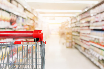 Empty shopping cart with abstract blur supermarket discount store aisle and product shelves...