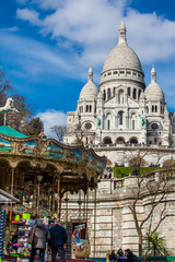 PARIS, FRANCE - MARCH, 2018: Carrousel and the Sacre Coeur Basilica at the Montmartre hill  in...