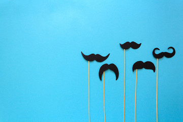 Paper mustache on booth props on blue paper background. Cut out style. Movember concept. Top view. Flat lay. Copy space