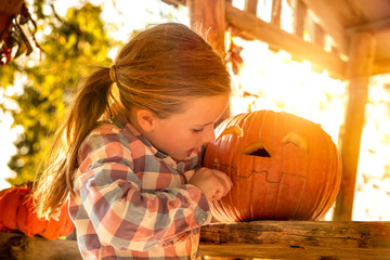 Little girl carving Halloween pumpkin outdoors.