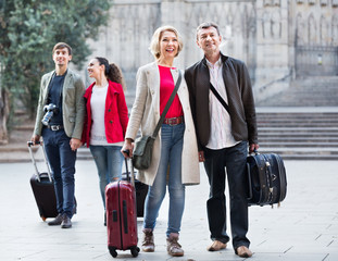 Two couples with baggage sightseeing and smiling