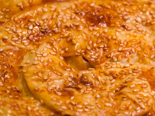 Bun is sprinkled with sesame, macro, background. Sesame bun top view macro texture background. Appetizing ruddy buns with sesame seeds, homemade pastries. Freshly baked wheat buns with sesame seeds.