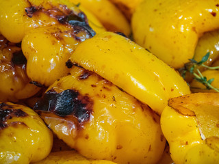 Freshly baked yellow peppers close up. Roasted bell yellow peppers with herbs. Baked Bulgarian pepper on fire. Grilled yellow paprika backgrund close up. Top view roasted yellow pepper.