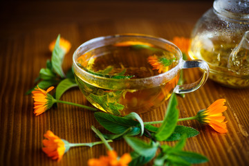 fresh hot tea with calendula on a wooden table