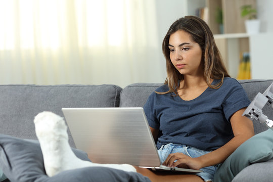 Serious desabled woman using a laptop at home